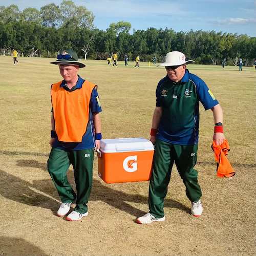 David Hughes and Dylan Gangell running the drinks eski out to the middle during a break in the match