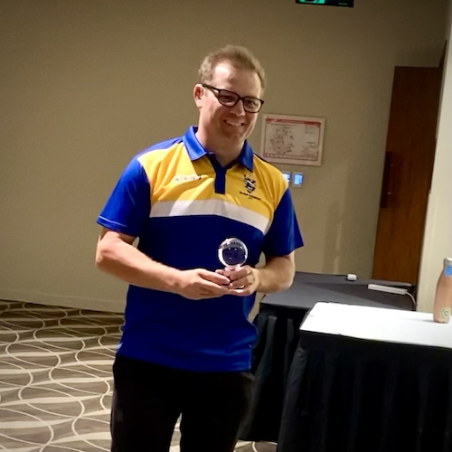 ACT CATS player Mathew Kent holding his glass trophy (looks like a cricket ball) for being awarded best B2 player of the tournament